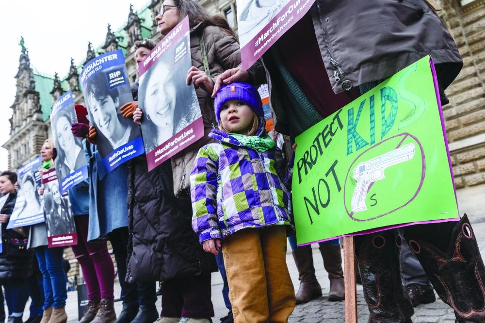 dpatop - Protesters hold pictures of people killed during school shootings in US during the "March for our Lives" for stricter gun control in the US in front of City Hall, in Hamburg, Germany, 24 March 2018. Photo: Markus Scholz/dpa