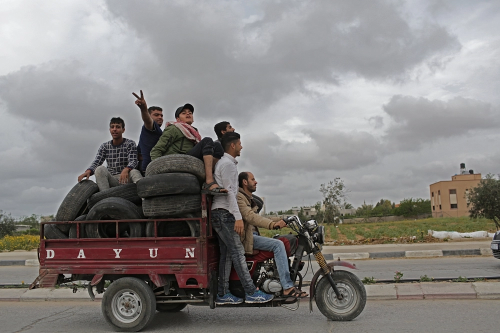 فلسطينيون ينقلون الإطارات إلى حدود قطاع غزة (إ ب أ)