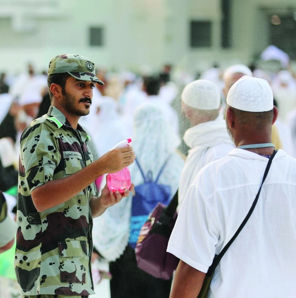 أحد رجال قوات الطوارىء يلطف الهواء للزوار والمعتمرين                    (أنس الحارثي)