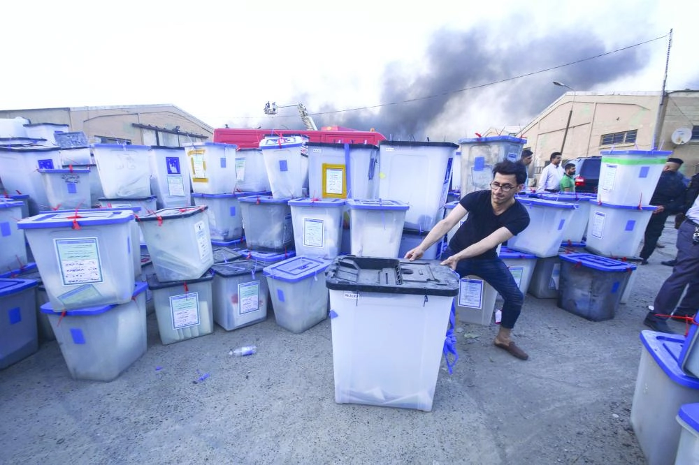 A man moves a ballot box as smoke rises from a fire that broke out at Baghdad's largest ballot boxes warehouse in Baghdad, Iraq, 10 June 2018. Iraq's parliament voted on Wednesday in favor of a manual ballot recount amid fraud allegations. Photo: Ameer Al Mohammedaw/dpa