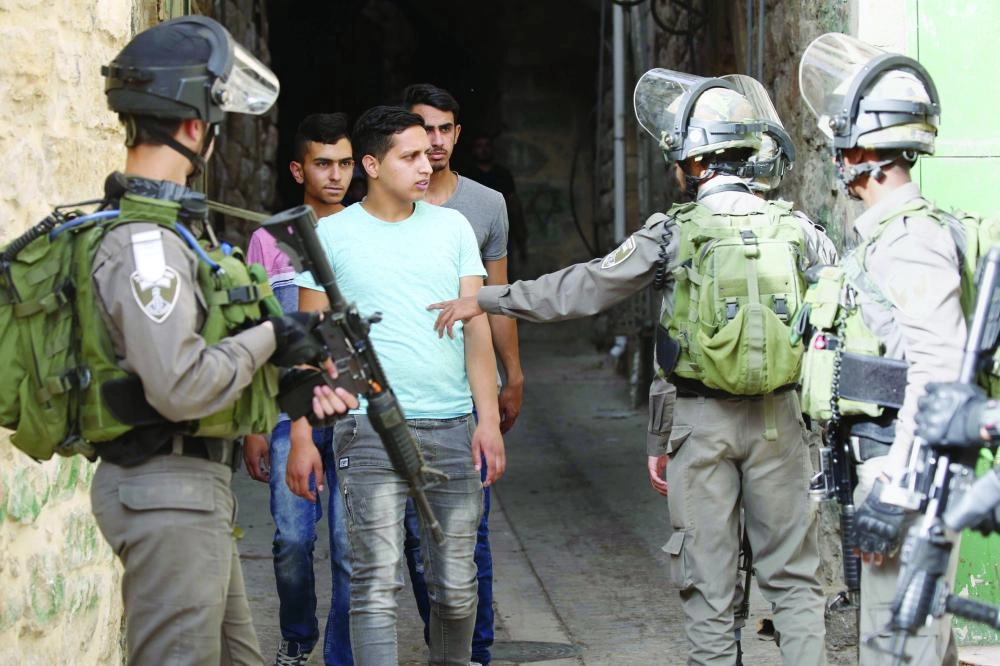 dpatop - Israeli soldiers speak with Palestinian men as they patrol on the streets of the Old City of the West Bank city of Hebron, 23 May 2018. Photo: Wisam Hashlamoun/APA Images via ZUMA Wire/dpa