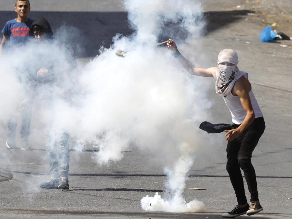 فلسطينيون يرشقون جنود الاحتلال بالحجارة خلال اشتباكات اندلعت في الخليل أمس (إ ب أ)