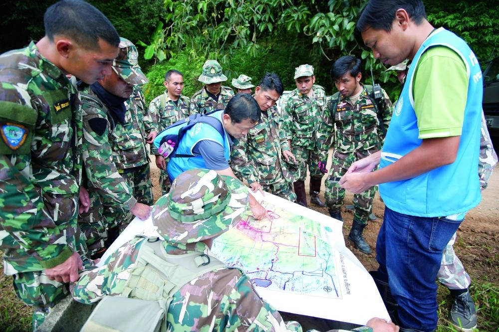 epa06870439 Thai forest rangers examine a map as they view a possible drilling option during the ongoing rescue operations for the child soccer team and their assistant coach, at a mountain forest near Tham Luang cave in Khun Nam Nang Non Forest Park, Chiang Rai province, Thailand, 07 July 2018. Operations are underway to safely bring out the 13 members of youth soccer team including their assistant coach who have been trapped in Tham Luang cave since 23 June 2018.  EPA/RUNGROJ YONGRIT