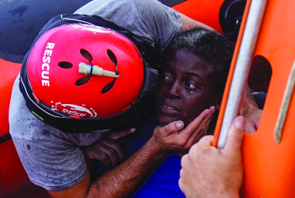 A crew member of NGO Proactiva Open Arms rescue boat embraces African migrant in central Mediterranean Sea