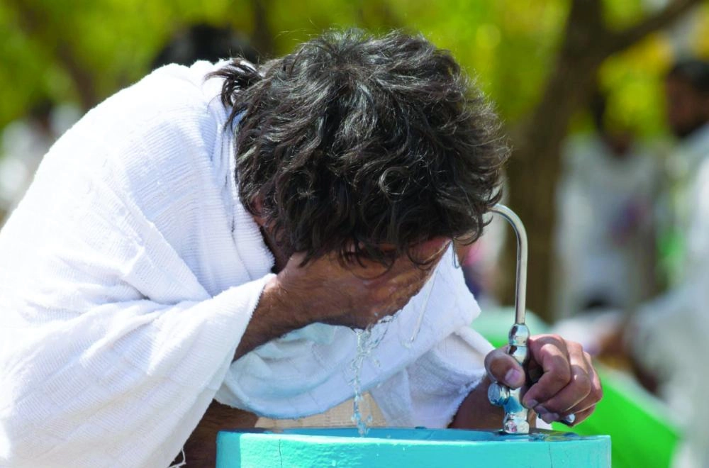 حاج يروي عطشه من إحدى برادات المياه بعرفات 