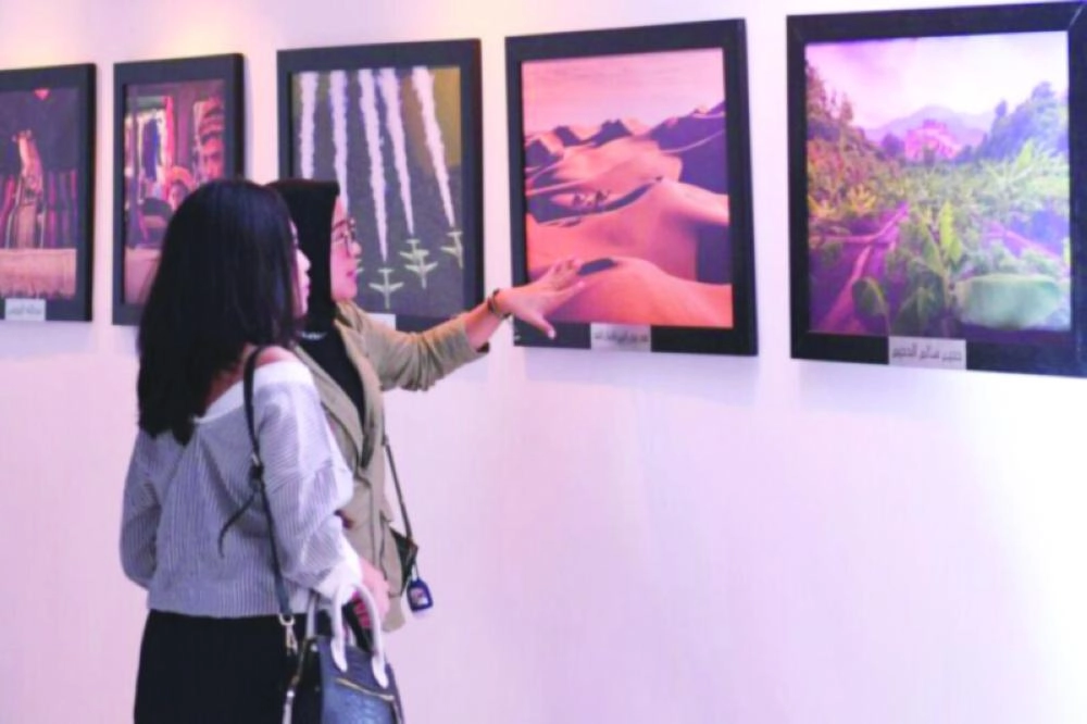 زائرتان تطالعان اللوحات الفنية المعروضة