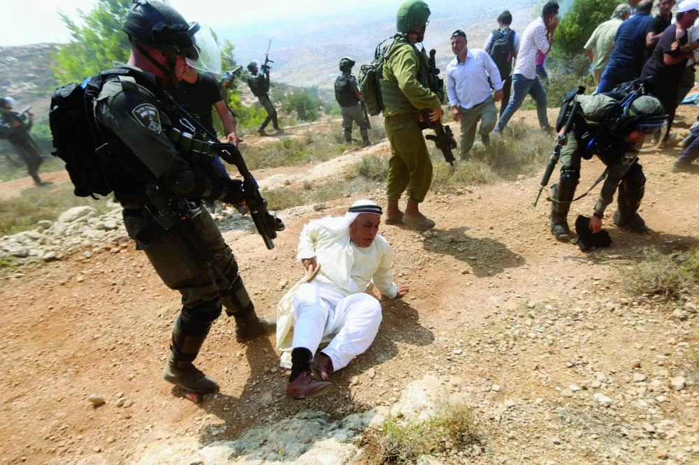 An Israeli soldier scuffles with a Palestinian protester during a protest against Jewish settlements in the village of Ras Karkar, near the West Bank city of Ramallah, 31 August 2018. Photo: Shadi Hatem/APA Images via ZUMA Wire/dpa