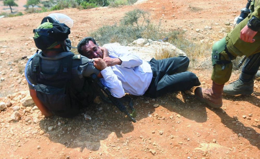 An Israeli soldier scuffles with a Palestinian protester during a protest against Jewish settlements in the village of Ras Karkar, near the West Bank city of Ramallah, 31 August 2018. Photo: Shadi Hatem/APA Images via ZUMA Wire/dpa