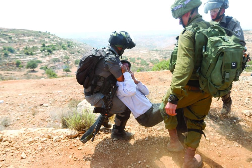 Israeli soldiers scuffle with a Palestinian protester during a protest against Jewish settlements in the village of Ras Karkar, near the West Bank city of Ramallah, 31 August 2018. Photo: Shadi Hatem/APA Images via ZUMA Wire/dpa