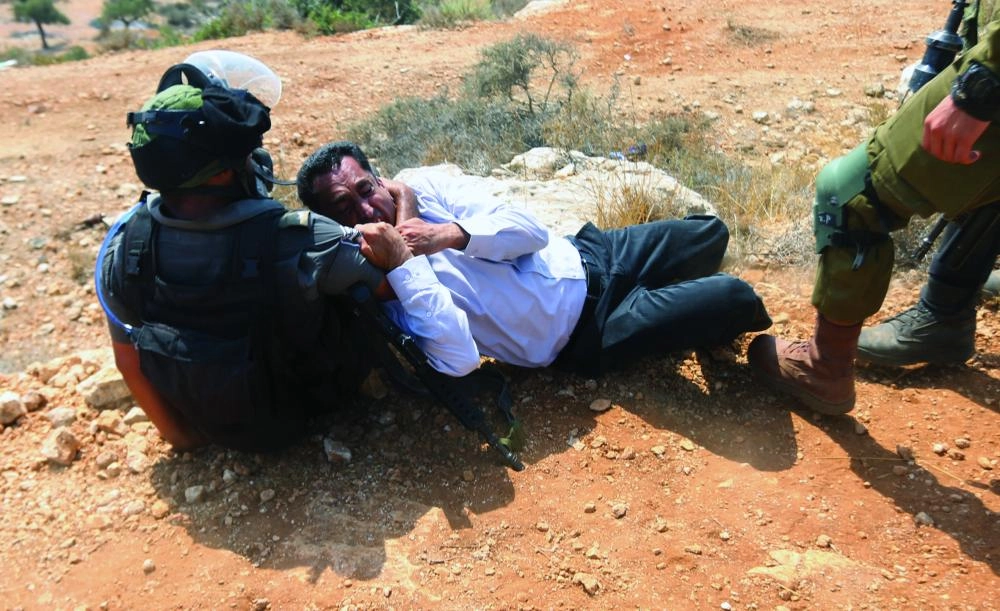 An Israeli soldier scuffles with a Palestinian protester during a protest against Jewish settlements in the village of Ras Karkar, near the West Bank city of Ramallah, 31 August 2018. Photo: Shadi Hatem/APA Images via ZUMA Wire/dpa