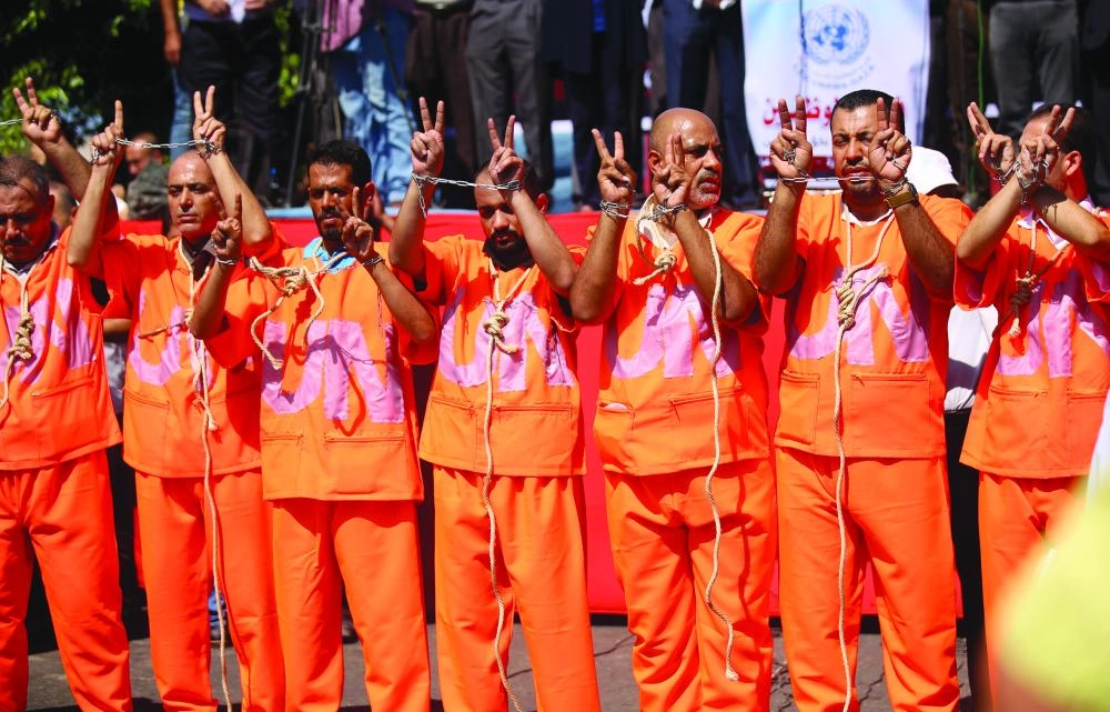 19 September 2018, Palestinian Territories, Gaza: Employees of United Nations Relief and Works Agency (UNRWA) wear orange jumpsuits with hands chained and rope around the neck during a protest against job cuts in front of UNRWA headquarter in Gaza City, Gaza Strip, 19 September 2018. Photo: Dawoud Abo Alkas/APA Images via ZUMA Wire/dpa