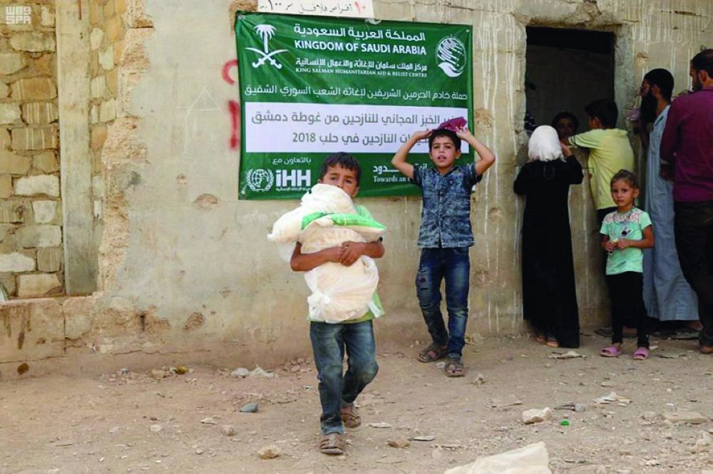 أطفال من اللاجئين السوريين يتسلمون نصيبهم من الخبز (واس)