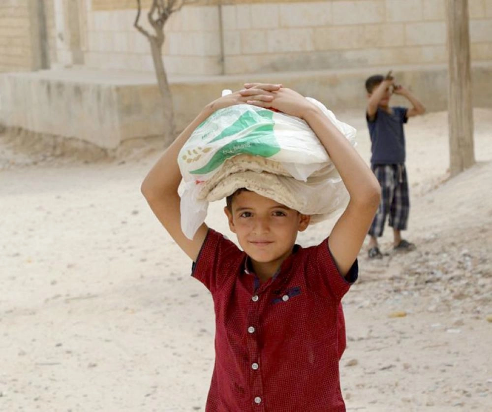 طفل من اللاجئين عقب تسلم الخبز الذي وزعه مركز الملك سلمان للإغاثة (واس)