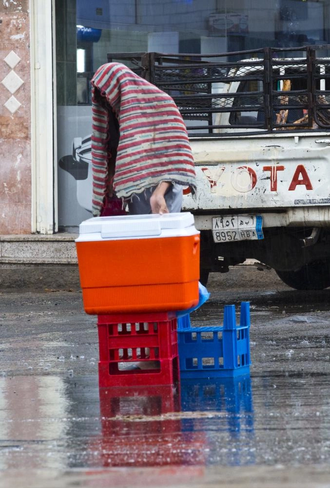 بائع يحاول الاحتماء من المطر (أنس الحارثي)