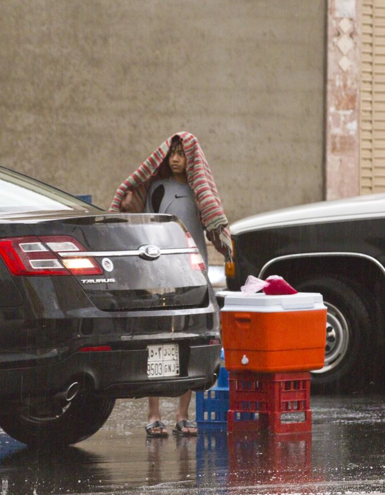 صبي يحتمي من المطر أمس (أنس الحارثي)