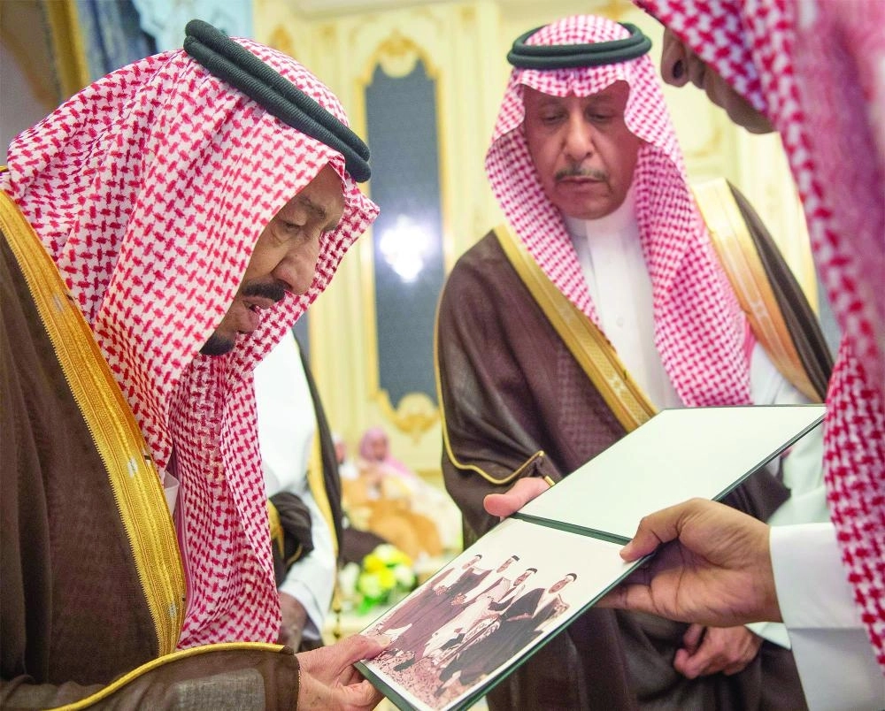 خادم الحرمين مطلعا على أحد الصورخلال الاستقبال (واس)