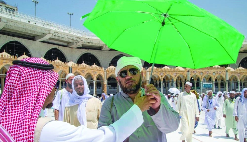 أحد موظفي رئاسة شؤون الحرمين يقدم الخدمة لحاج في ساحة المسجد الحرام (واس)