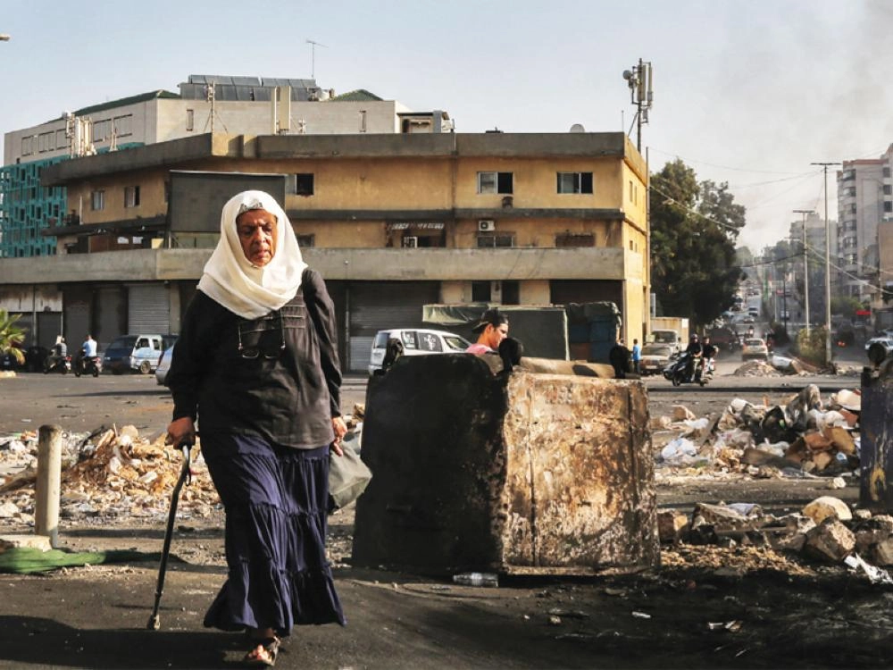 مسنة لبنانية تسير عبر حاجز إثر إغلاق الطرق المؤدية إلى بيروت لليوم الثالث على التوالي بسبب المظاهرا ت (د ب أ )