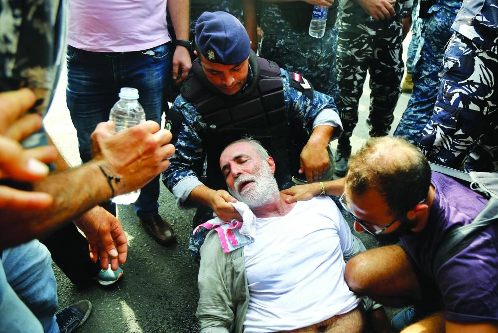 26 October 2019, Lebanon, Beirut: A riot police officer wipes the face of an old demonstrator after fainting while Lebanese riot police evacuate protestors by force to reopen a highway they are blocking. For the 10th consecutive day demonstrators are still in the streets across Lebanon to protest the country's dire economic conditions. Photo: Marwan Naamani/dpa