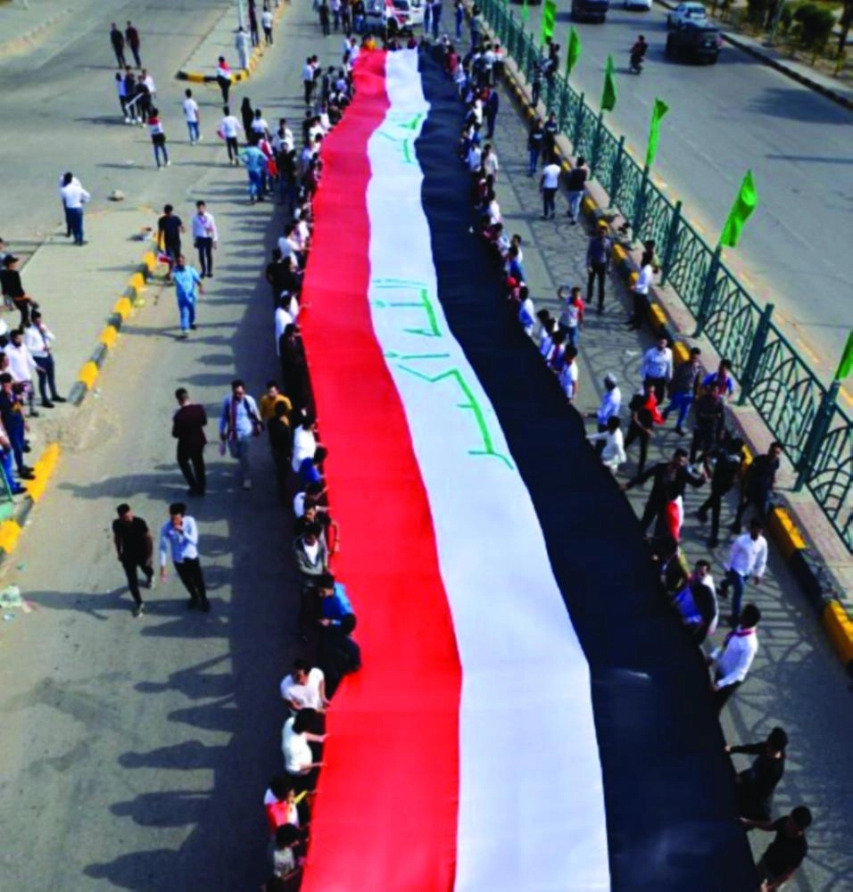 طلاب يشاركون في مظاهرات العراق ويحملون علم بلدهم (أ ف ب)