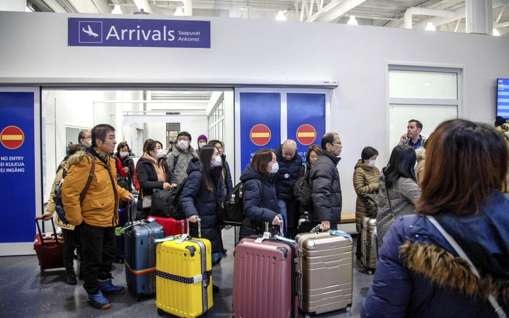 مسافرون يرتدون أقنعة عند وصولهم إلى مطار إيفالو ( د ب أ )