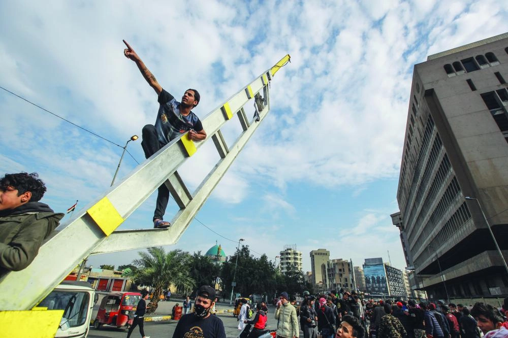متظاهر عراقي يتسلق عمودا معدنيا وآخرون يواصلون حراكهم (د ب أ)