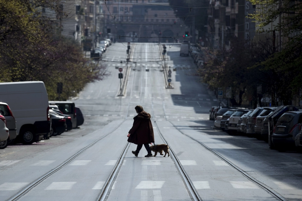 رجل يسير مع كلبه في شارع فاضي تماما بروما    (د ب أ)