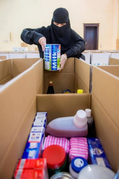 إحدى عضوات فريق مجلس فتيات القصيم تشارك في توزيع السلال الغذائية في حملة نهر العطاء 