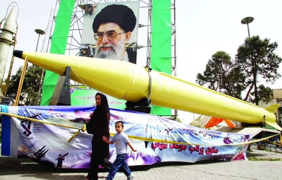 






سيدة وطفلها يمران من أمام صورة خامنئي وأحد هياكل الصواريخ