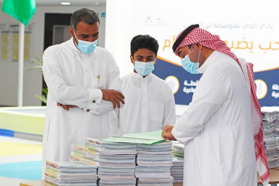 أولياء أمور مع أبنائهم لتسلم كتبهم الدراسية في أول يوم من عودة الهيئة الإدارية