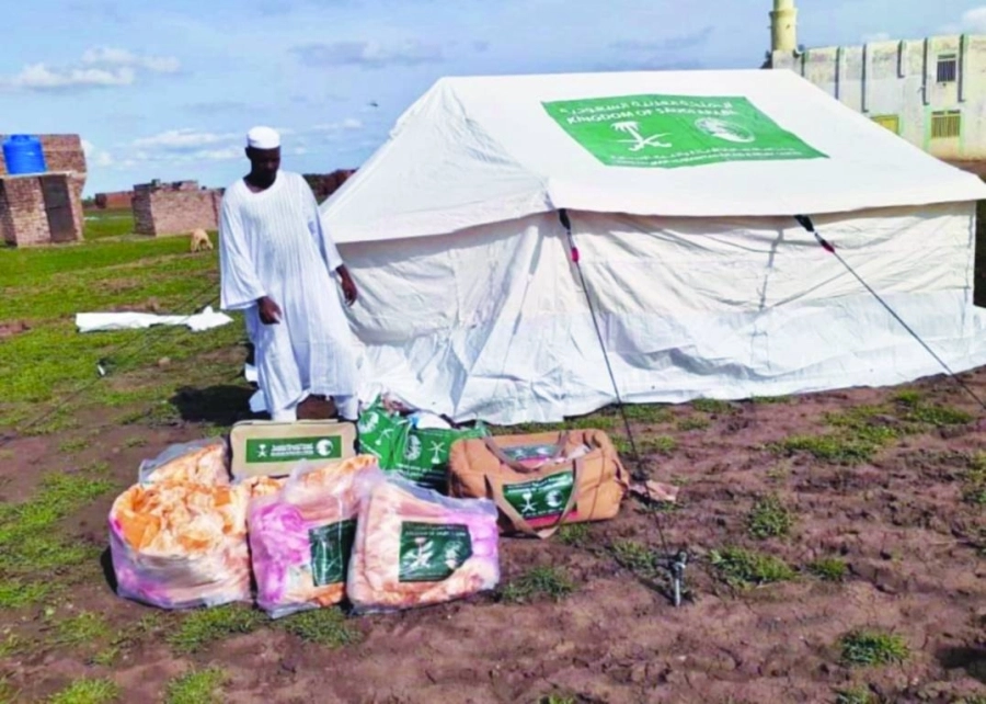 سوداني يقف أمام بطاطين مواد إغاثية تسلمها من المركز (واس)