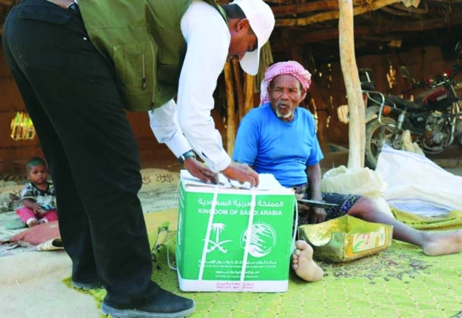 أحد أفراد المركز يسلم مسنا يمنيا سلة غذائية (واس)