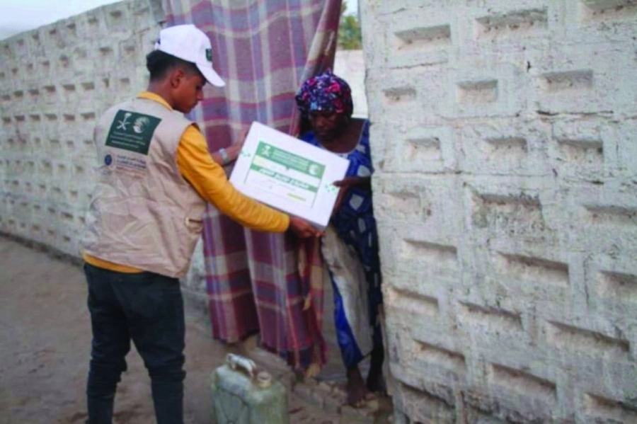 متطوع يسلم كرتونة تمور لسيدة يمنية (واس)