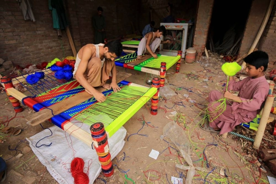 أحد الأطفال يشارك في صنع أسرة تقليدية لبيعها في باكستان
