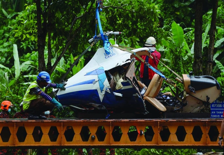 عمال ينقلون حطام طائرة هليكوبتر تحطمت في منطقة تامان ملاواتي بماليزيا بعد اصطدامها بأخرى في الجو، حيث مات رجلان ونجا اثنان

