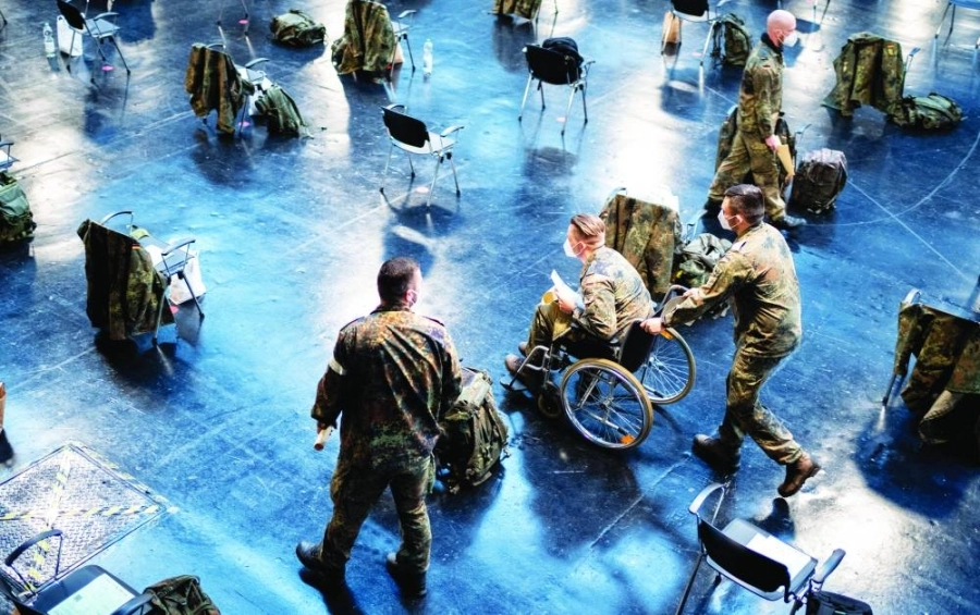 جنود من القوات المسلحة الألمانية يرتدون أقنعة للوجه ينتظرون بدء التشغيل التجريبي في مركز التطعيم ضد كورونا في برلين اعتبارا من 27 ديسمبر الجاري.
