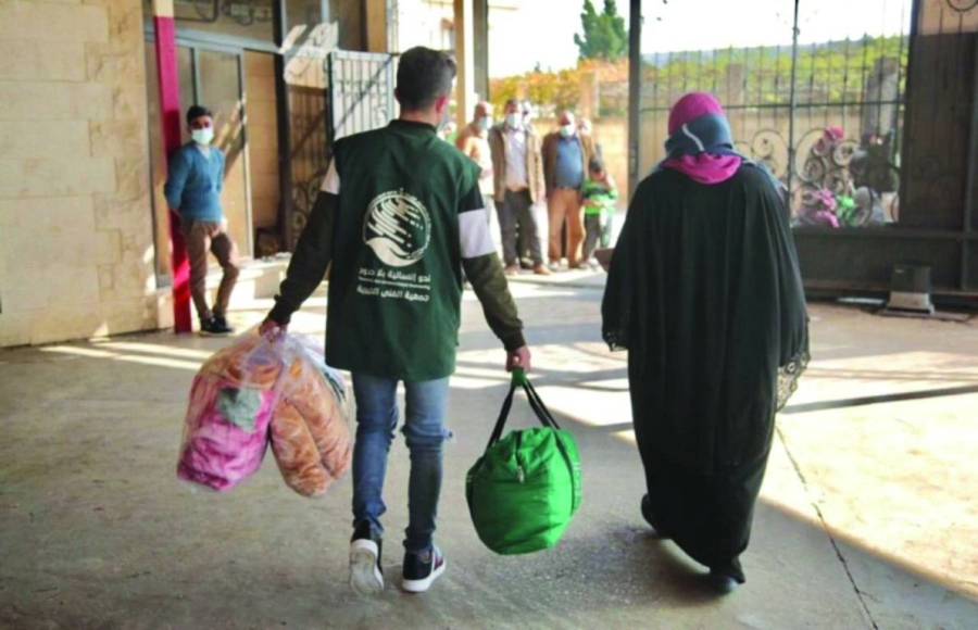 متطوع يساعد لبنانية على إيصال حقيبتها الشتوية (واس)