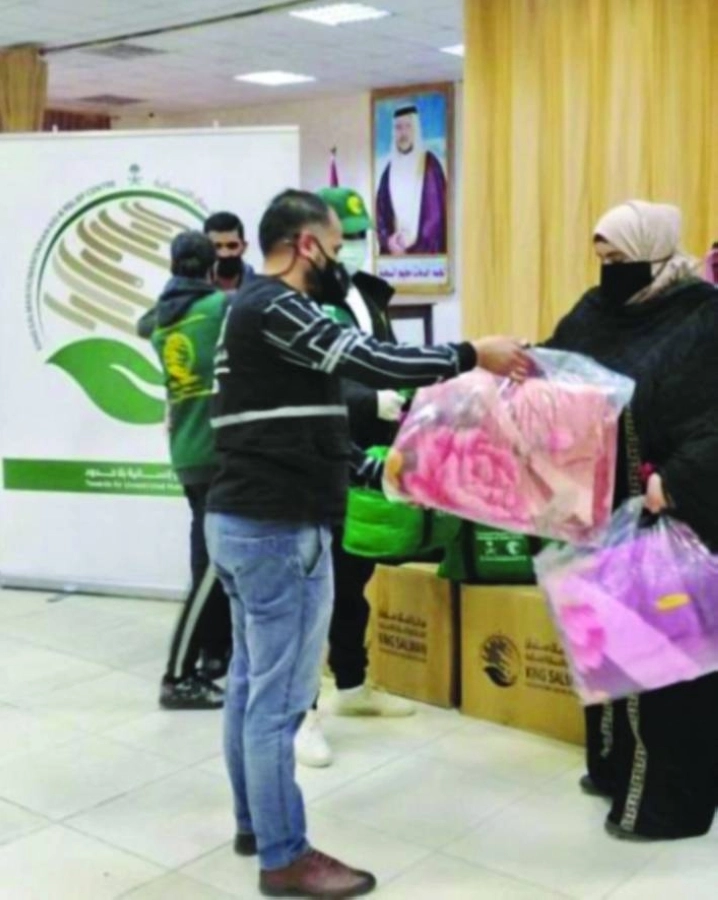 متطوع يسلم سيدة أردنية حقيبة الشتاء (واس)