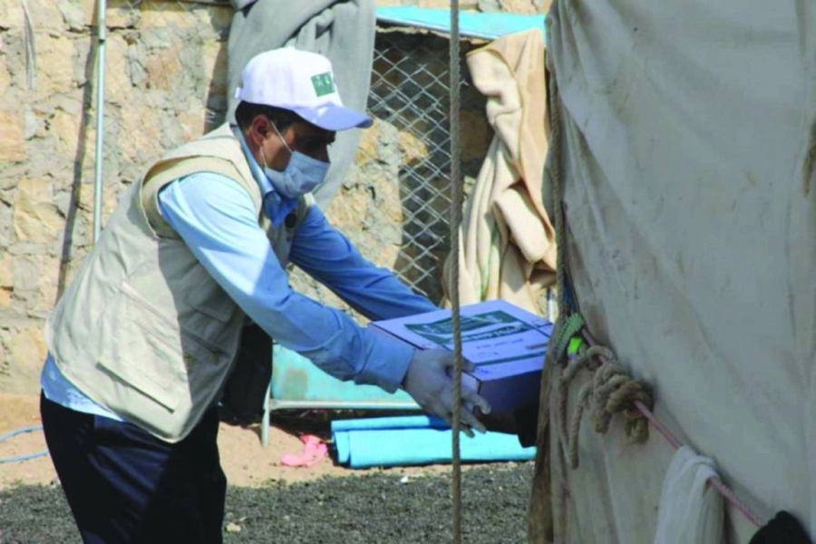 متطوع يسلم أحد النازحين كرتون تمر (واس)