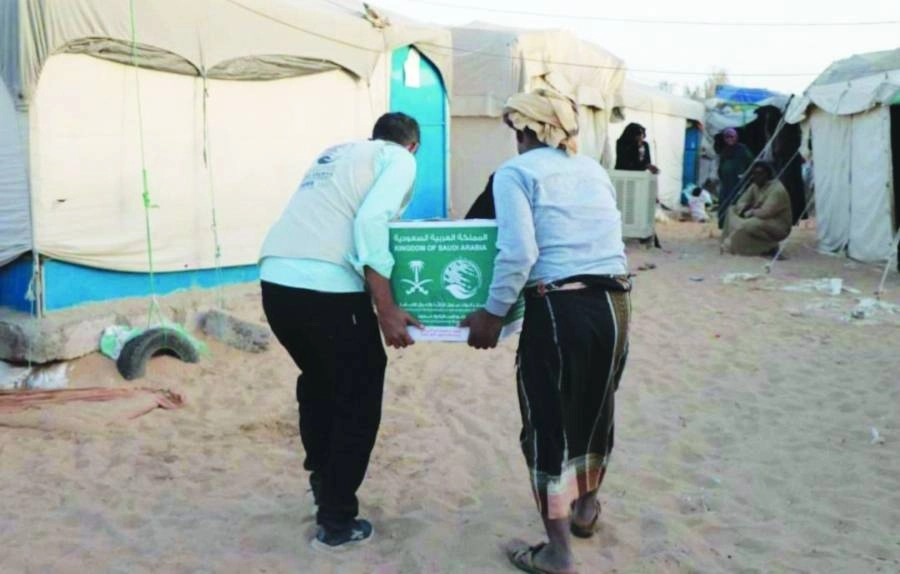 متطوعان يحملان سلة لأحد خيام اللاجئين (واس)