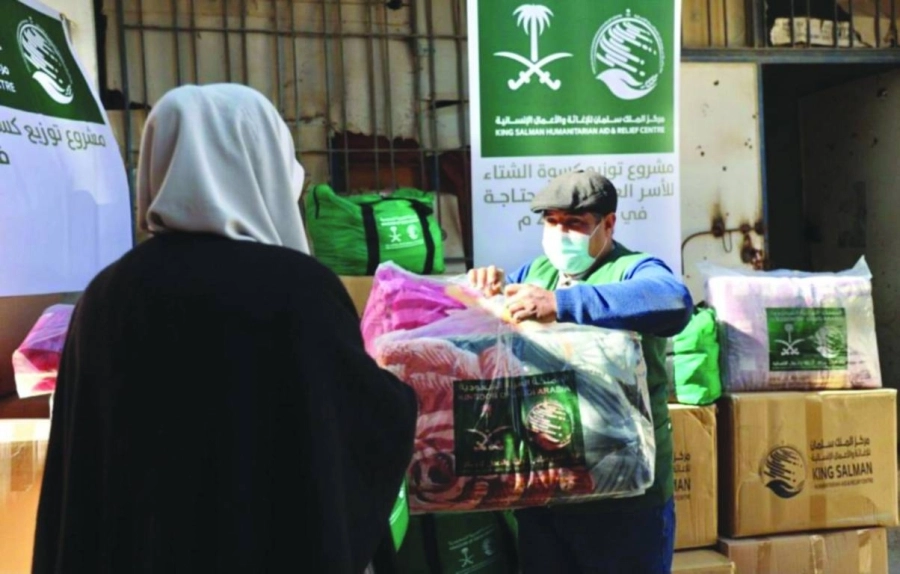 متطوع يسلم إحدى السيدات بطانية شتوية  (واس)