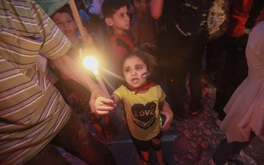  فتاة تحمل شمعة خلال وقفة احتجاجية أمام منزل دمرته الغارات الاسرائيلية (د ب أ)