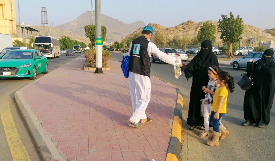 عدد من منسوبي الجمعيات الخيرية خلال توزيع وجبات إفطار صائم في شوارع العاصمة المقدسة.
