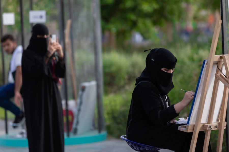 فنانة خلال رسم أحد زوار حديقة الأمير ماجد بجدة ضمن البرامج المتنوعة والعروض المشوقة لموسم جدة.
