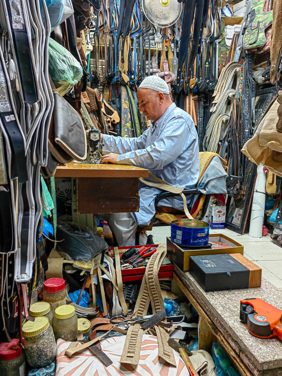 مسن يحترف عمل الخرازة وسط لفائف الجلديات المتدلية بكل شغف وتركيز، في أحد الأسواق الشعبية بالطائف. (أنس الحارثي)