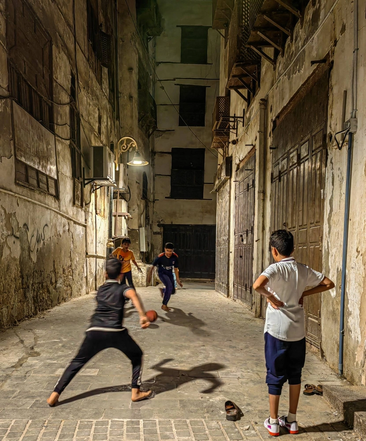 أطفال يلعبون مباراة كرة قدم في وقت متأخر من الليل بين أزقة تاريخية جدة. 