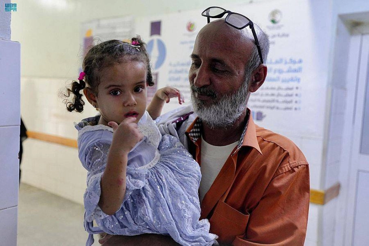 

 يمني يحمل ابنته قبل العملية الجراحية