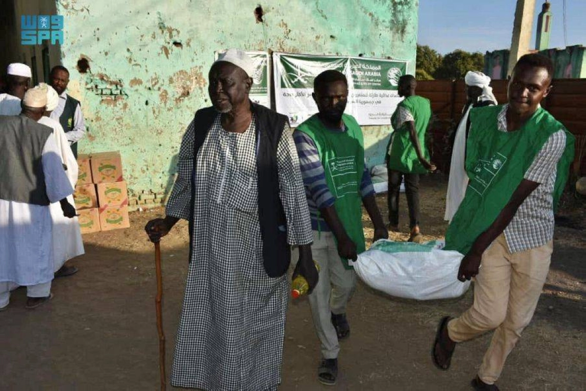 متطوعان يساعدان مسن على نقل المواد الغذائية