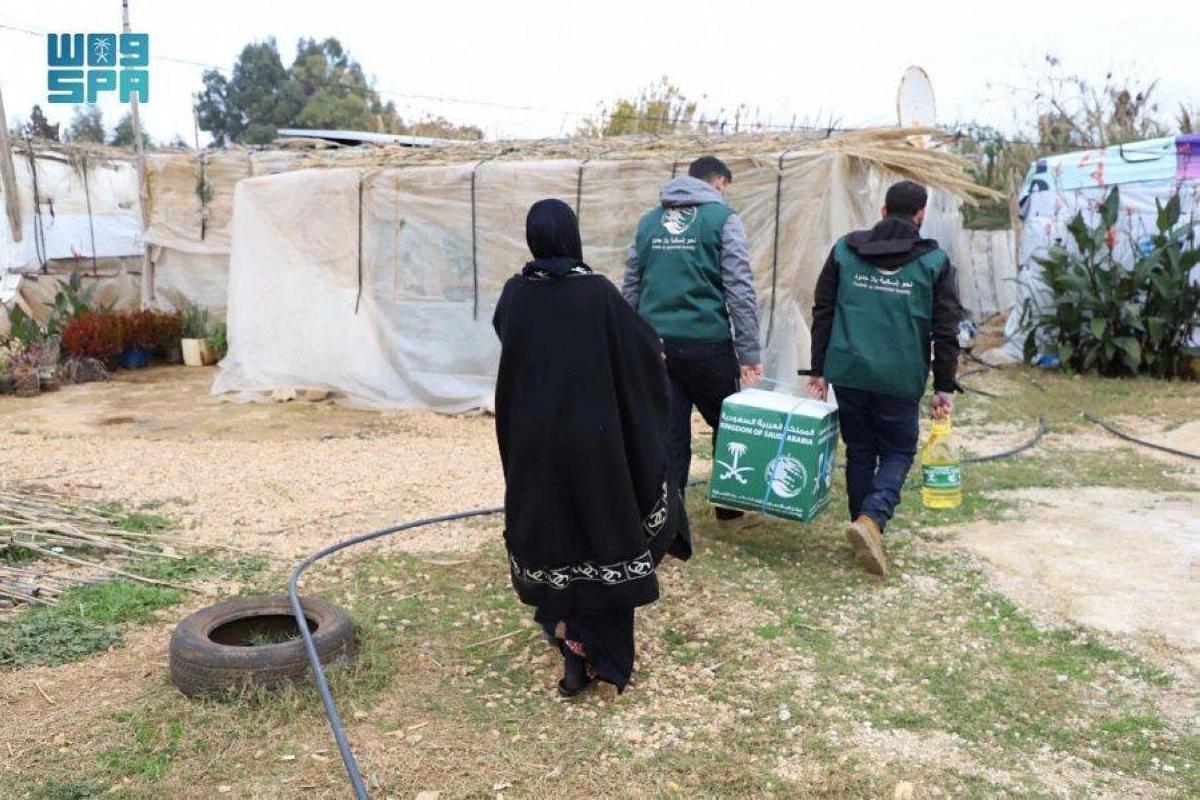 متطوعان يحملان المواد الغذائية لسيدة سورية