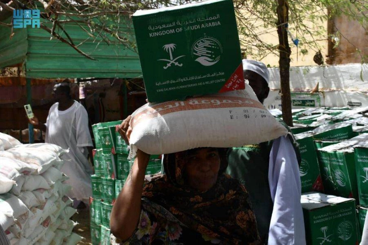 سودانية تحمل المواد الغذائية من مركز الملك سلمان للإغاثة (واس)